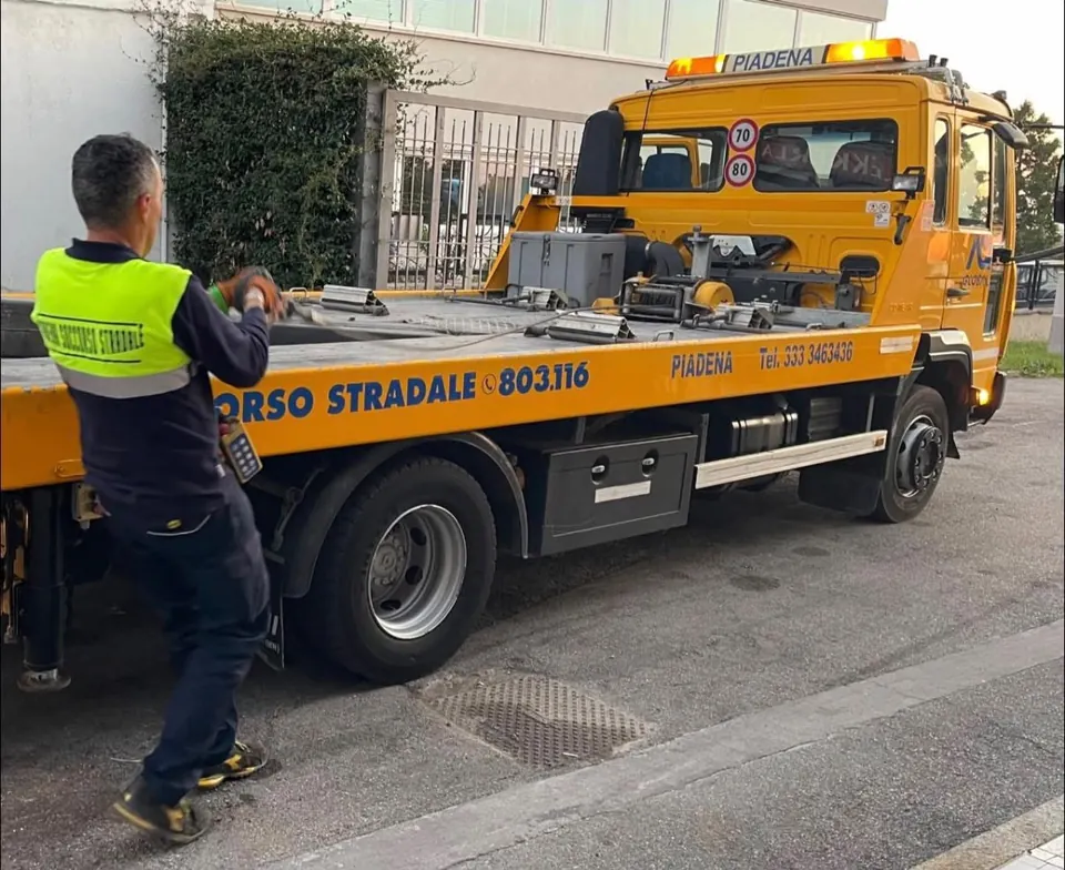 Operatore accanto a un carro attrezzi giallo con pianale